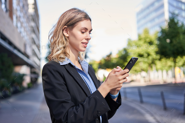 Profile portrait of young saleswoman, corporate lady in suit, using mobile phone, reading on