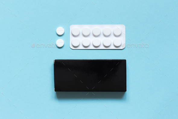 Black carton box, blister and white pills on a blue background. Medications. Mock-up.