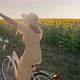 Happy Woman in Yellow Dress Riding Retro Styled Bicycle on Country Road Near Sunflowers Field - VideoHive Item for Sale