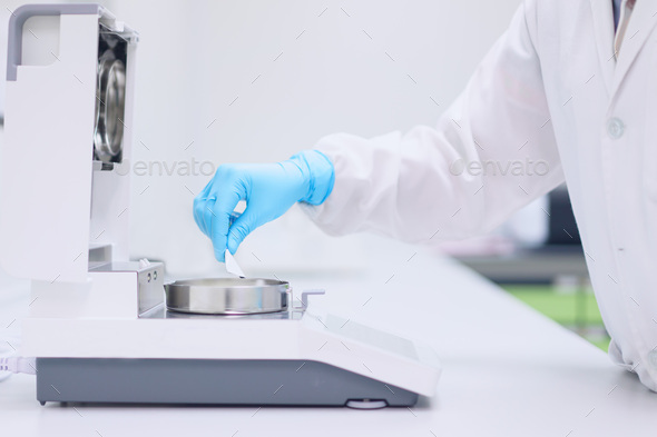 Unidentified operator is testing moisture content in sample with automatic moisture balance.an - Stock Photo - Images