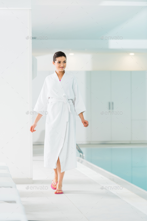 attractive woman in bathrobe walking near swimming pool Stock Photo by LightFieldStudios