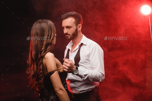 seductive young couple in red smoky room