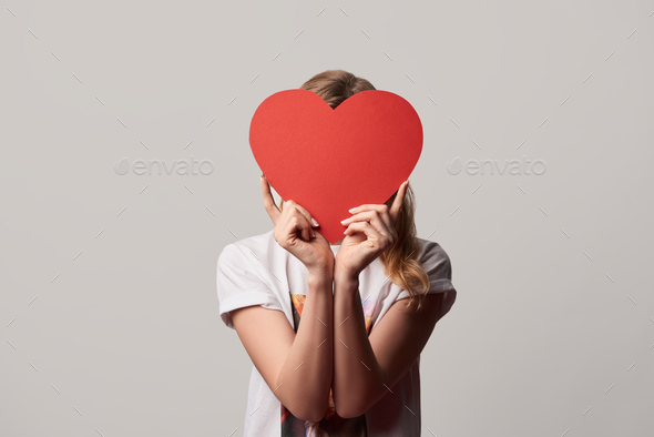 girl with obscure face and empty paper cut heart card isolated on grey