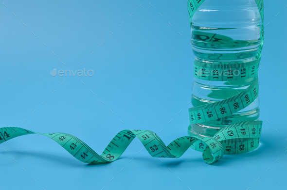 tape measure and mineral water bottle isolated on a blue