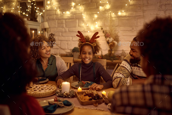 Happy African American extended family enjoying in conversation at dining table on Thanksgiving.