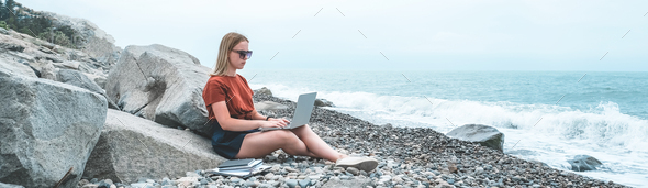 Remote work.Girl freelancer works remotely on the sea shore.workation, remote work,WFVH,
