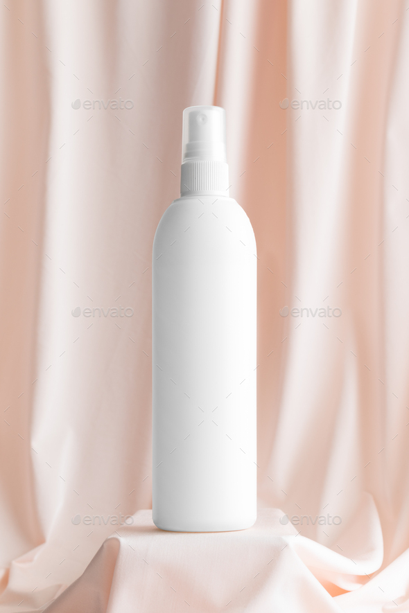 White cosmetic spray bottle mockup on the soft pink textile.