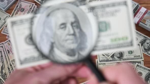 One Hundred Dollars Inspecting Under Magnifying Glass on Money Background alt