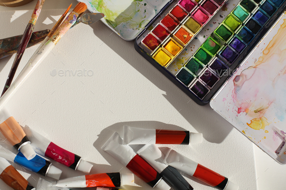 Creative mess in artistic workshop. Empty canvas, acrylic paints, brushes, .
