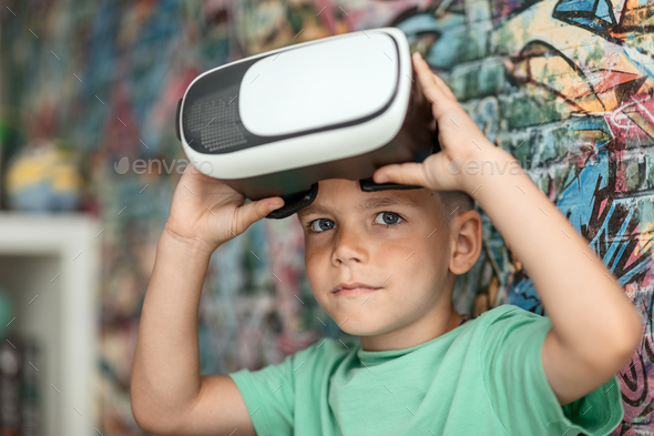 a boy child looks out of a virtual reality helmet