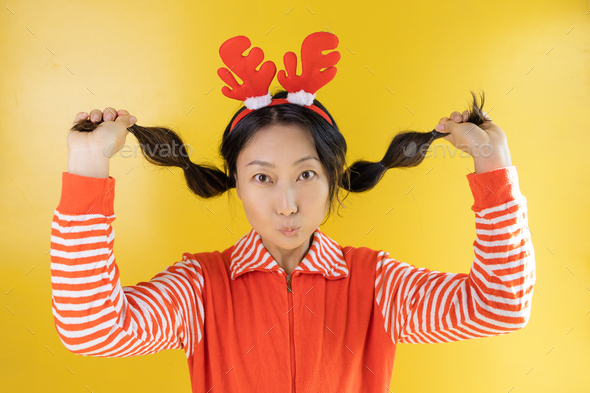 Photo of an excited asian girl in a Christmas sweater, pullover, deer, headband, new year time, winn