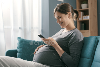 Smiling pregnant woman chatting with her smartphone