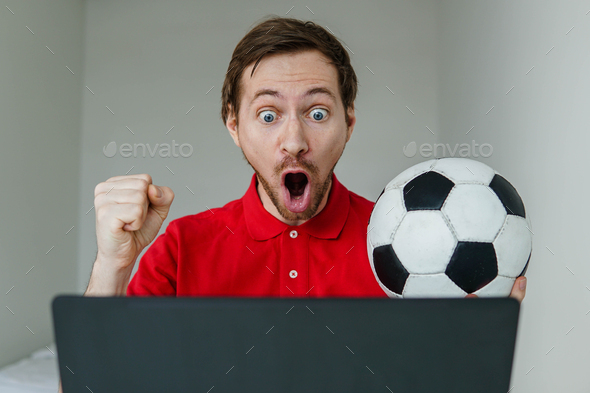 Excited man fan support his football team hold in hand soccer ball watch tv live stream on laptop. - Stock Photo - Images