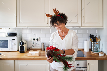 Senior woman holding Christmas wreath in the kitchen of home