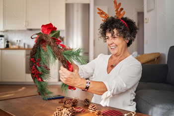A senior woman making a Christmas wreath to decorate her home