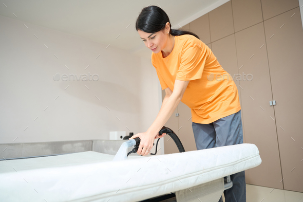 Female performing general cleaning of sleeping mattress