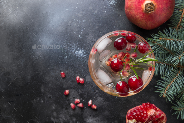 Pomegranate Christmas cocktail with rosemary, club soda on black. Close up. View from above.