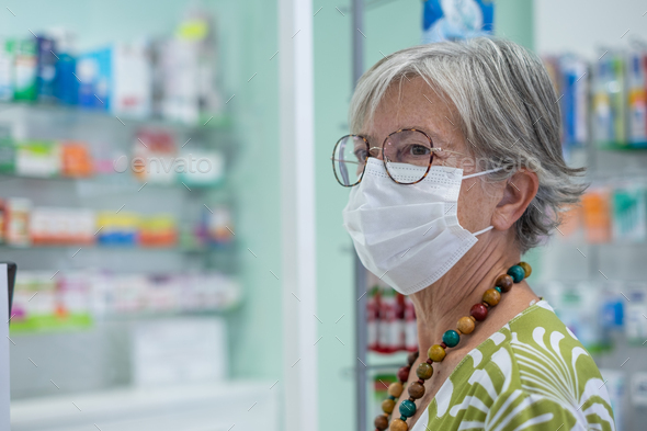 Portrait of senior woman wearing mask shopping medical products in pharmacy