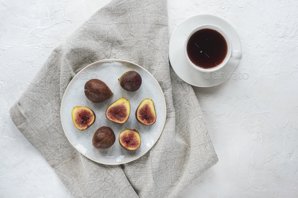 Still life with coffee cup and figs on white textured table. Top view ...