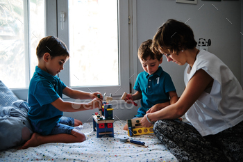 a mother playing with toys with her children on the bed at home