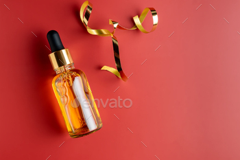 Face serum in dropper botle with pipette on red background with serpentine. Concept of creative 