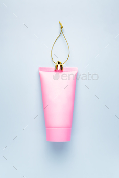 Festive Christmas background with Christmas decoration and pink plastic cream squeze tube of cream.