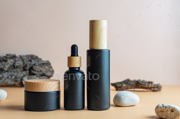 Set of natural cosmetics in black matte glass package on beige background with bark of the tree 