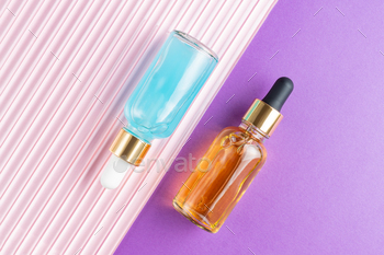 Beauty collagen face serum in a glass dropper bottles on double purple and pink background. Trendy 