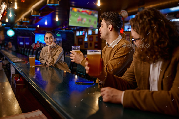 Young male friends flirting with woman at bar counter