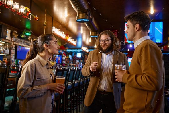 Cheerful friends talking drinking draft beer in pub