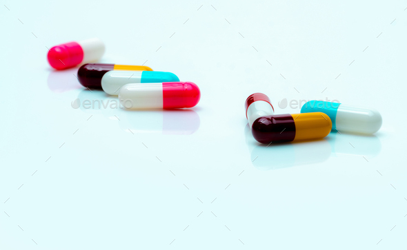 Multi-color antibiotic capsule pills spread on white background. Antibiotic drug resistance.