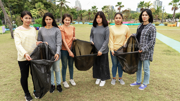 Asia Woman Group Team Volunteer picking up Trash plastics garbage plastic waste.