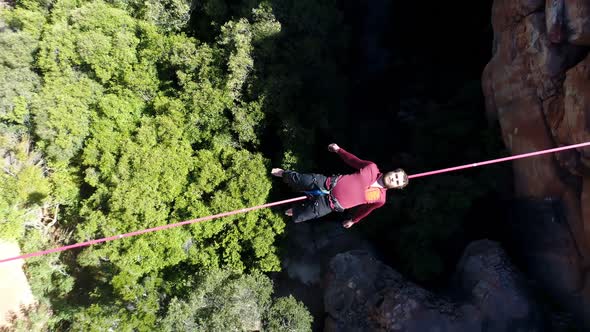 Male highliner lying on a rope over rocky mountains 4k alt