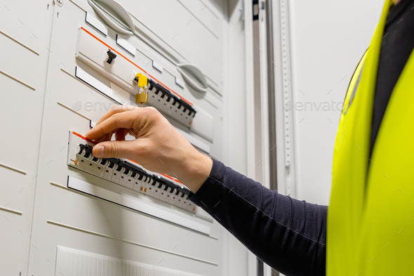Close-up of male Technician Checking Electric Fuse Board In Server Room - Stock Photo - Images