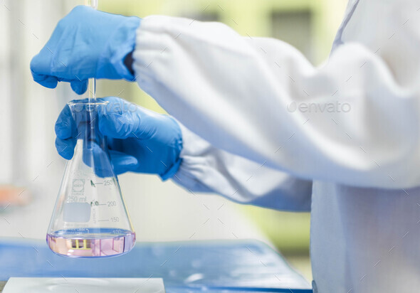 Chemist hands wear the blue nitrile gloves and working by titrating the sample solution. - Stock Photo - Images