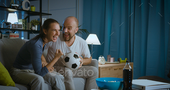 Happy couple watching a football match on TV