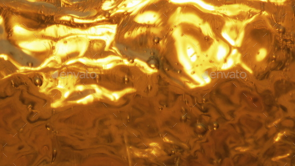 Splashes light beer glass closeup. Golden carbonated beverage swashing waving