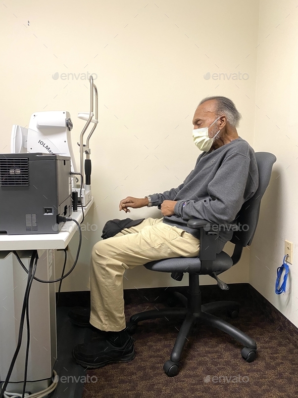 Senior adult male sitting down waiting for an eye exam at ophthalmology center