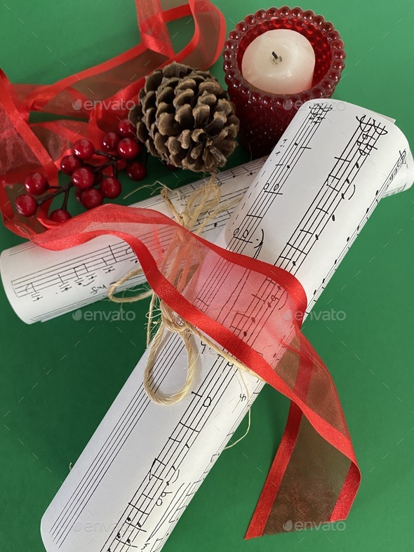Sheet music on green background with candle and pinecone