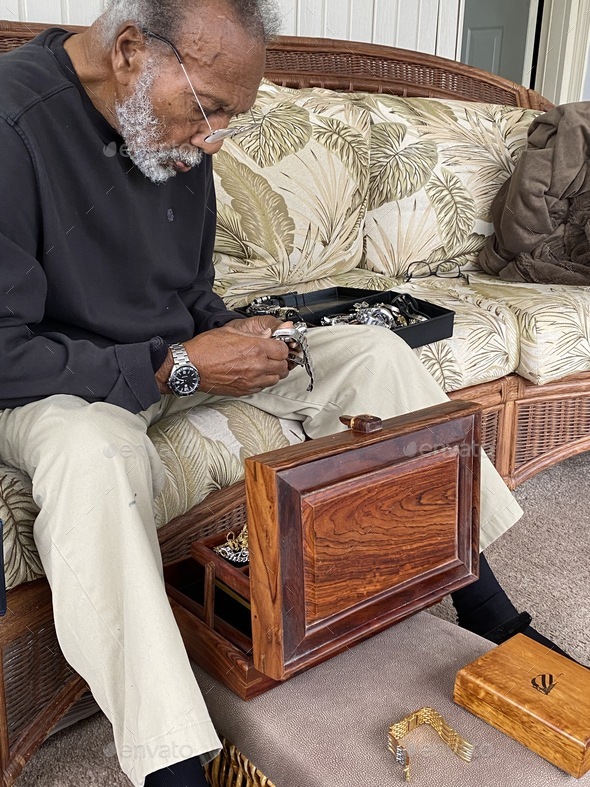 Senior adult male sitting down checking his luxury watches if needed battery