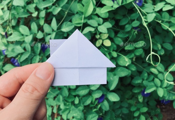 A man holding a house origami. Real estate concept. House for sale or rent