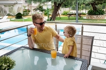 Dad and cute baby girl drinking orange juice on holiday