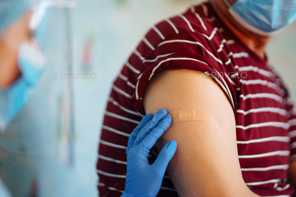 Close up photo of senior patient arm with doctor`s hands making injection. Covid 19 vaccination.