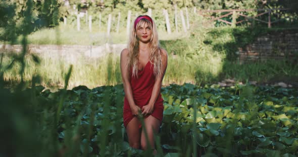 Young woman in red dress in nature, standing and smiling alt