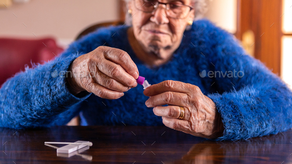 Old woman open a sample for covid-19 antigen diagnostic test device at home.