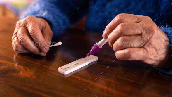 Old woman placing the sample into the covid-19 antigen diagnostic test device