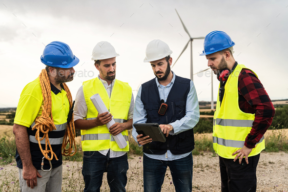 Team of engineers and technical workers working outdoors wind turbine farm planning construction