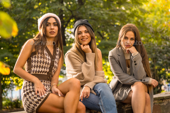 Portrait of carefree women friends in a park in autumn, fashionable autumn lifestyle positive energy