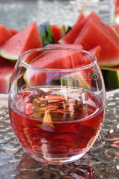 a glass of rose wine and watermelon pieces in the background