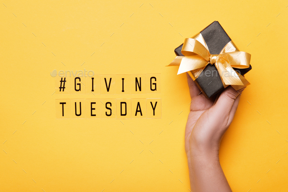 Giving Tuesday. Global day of charitable giving after Black Friday shopping day. hand holding gift